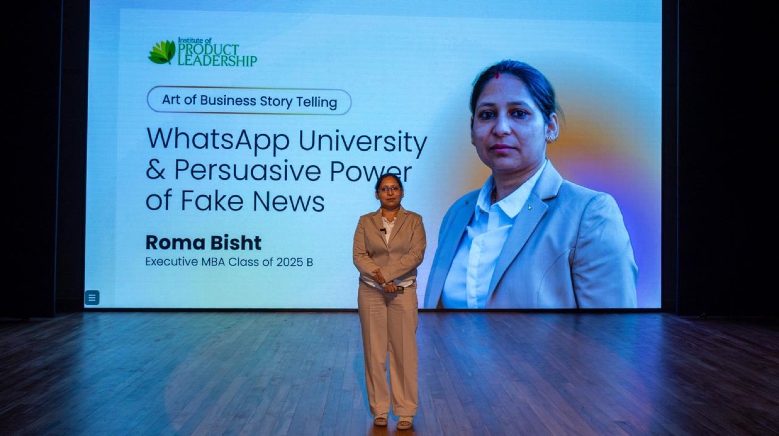 Roma Bisht on stage beside the Institute of Product Leadership title slide, Executive MBA Class of 2025 B